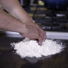 Hacer un volcán sobre la mesa con la mezcla de ingredientes secos. Agregar en el centro la leche, esencia de vainilla, te de azahar y los huevos uno a uno.