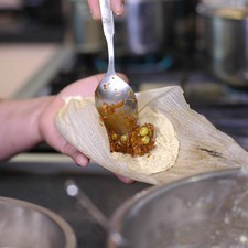 Agregar un poco de la carne en el centro. Doblar la orilla de la hoja sobre la otra para formar un tamal, doblar la punta de la hoja para que cubra la juntura.