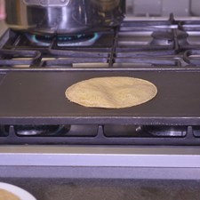 Poner a calentar el comal a fuego medio. Colocar una tortilla de maíz sobre el comal.