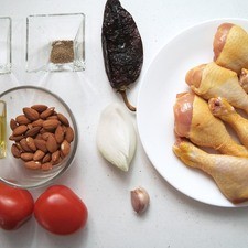 Ingredientes para receta 6 piezas de pierna de pollo 2 piezas de jitomate guaje 1 diente de ajo 1/4 pieza de cebolla blanca sal al gusto pimienta negra molida al gusto 1 pieza de chile ancho 1 cucharada de aceite de oliva 3/4 taza de almendra Nuevo