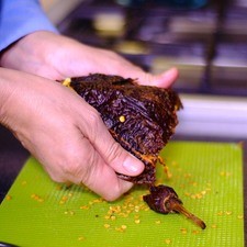Cortar el rabo del chile ancho con una tijera, abrir por un lado y retirar las semillas y las venas.