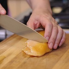 Colocar la media pechuga de pollo sobre la tabla para picar y hacer cortes en diagonal cuidando de no cortar totalmente la carne.