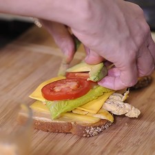 Colocar una rebanada de queso manchego, unas tiras de pollo, una rebanada de queso amarillo, una hoja de lechuga, rebanada de jitomate, rebanadas de aguacate.