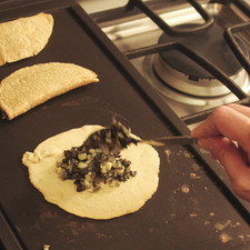 Colocar las tortitas sobre el comal un minuto y agregar un poco de cuitlacoche cocido, doblar a la mitad y sellar bien los bordes con forma de empanada. Dejar cocer por un lado y voltear la empanada.
