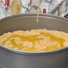 Derretir la mantequilla en una sartén pequeña y agregarla al molde con las migajas. Mezclar bien y presionar fuertemente contra la base del molde hasta formar una base de migajas bien compacta.