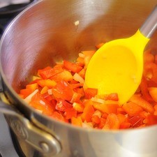 Calentar la cucharada de aceite en el sartén y cuando esté bien caliente sofreír la cebolla y el pimiento morrón picado durante un par de minutos o hasta que estén suaves.