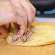Para armar las flautas, si no contamos con tortillas especiales ya que son más grandes, calentamos dos tortillas y las colocamos sobre la tabla de picar una sobre la otra. Rellenar con un poco de la carne deshebrada y enrollar para formar la flauta, y fijar con palillos.