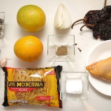 Ingredientes para receta 1/2 pieza de pechuga de pollo 4 piezas de chile ancho 2 cucharadas de ajonjolí 1/4 pieza de cebolla blanca 1 diente de ajo 1 vara de canela entera 1/4 cucharita de pimienta negra molida 1 pieza de clavo de olor 2 piezas de naranja sal al gusto 200 gramos de pasta de pluma La Moderna
