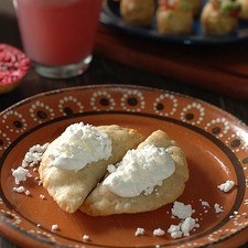 Para servir, colocar dos empanadas sobre el plato y añadir un poco de crema y queso fresco.