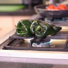 Para preparar las rajas, tostar los chiles sobre la lumbre directa de la hornilla dando vuelta con una pinza hasta que se vean negros por todas partes.