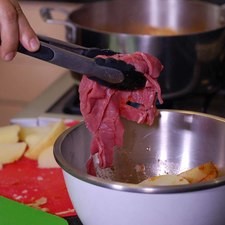 Agregar los gajos de papa y las tiras de carne a la mezcla de aceite y paprika y revolver bien. Dejar marinar durante 10 minutos.