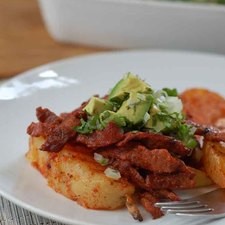 Para servir colocar papas y tiras de carne en un plato y añadir un poco de la mezcla de aguacate. Servir inmediatamente.