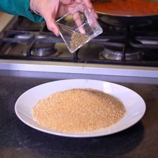 Colocar en un plato el pan molido, orégano y revolver.