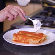Bañar con la salsa de jitomate y agregar un poco de crema y rebanadas de aguacate.