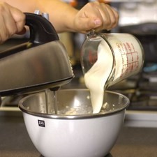 Añadir la crema poco a poco sin dejar de batir. Parar y bajar la mezcla de los lados, continuar batiendo hasta que la mezcla esté bien integrada.