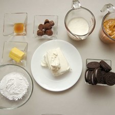 Ingredientes para para la masa 12 piezas de galletas oreo 3 cucharadas de mantequilla Ingredientes para para el queso 190 gramos de queso crema 100 gramos de crema para batir 1/2 cucharita de esencia de vainilla 1/2 taza de azúcar glass (pulverizada) 3/4 taza de mantequilla de cacahuate 10 piezas de chocolate resess