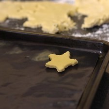 Enharinar ligeramente una superficie y extender la masa con un palote, cortar con un cortador de galletas en forma de estrella. y colocar sobre una charola para galletas.