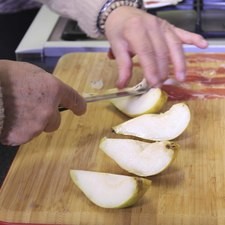 Para preparar los bocaditos de pera con jamón, partir las peras en cuatro partes y retirar la parte fibrosa del centro.