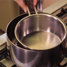 Para preparar la cobertura colocar la olla mediana sobre la estufa, agregar agua y poner dentro la olla chica flotando sobre el agua para lograr un efecto de baño María. Encender la estufa, una vez caliente el agua, poner el fuego bajo.