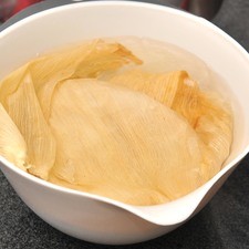 Poner a remojar las hojas de elote en agua bien caliente al menos 20 minutos para que se suavicen y sea más sencillo doblarlas.