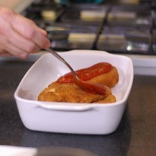 Colocar en un refractario las pechugas de pollo empanizadas y añadir un poco del puré de tomate sobre cada una de ellas. Rs 1482331637