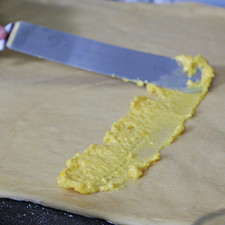 Untar una capa delgada de crema pastelera sobre el rectángulo de masa, dejando una orilla sin untar de unos 3 centímetros en uno de los lados largos.