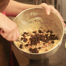 Añadir las pasas y las nueces e incorporar. Embarrar bien el molde refractario para horno con mantequilla y espolvorear con harina para que no se pegue el budín. Agregar la mezcla y hornear a 350°F (175 °C) durante 35 a 45 minutos. El budín debe quedar húmedo.