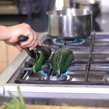 Asar los chiles poblanos directamente sobre la hornilla de la estufa, dándoles vuelta con una pinza hasta que la piel esté tostada por todos lados. Rs 1487259672