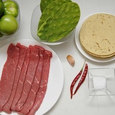 Ingredientes para receta 6 piezas de bistec de res 8 piezas de penca de nopal 6 piezas de tomate verde (tomatillo) 2 piezas de chile de árbol seco 1 diente de ajo sal al gusto 2 cucharadas de aceite de oliva pimienta negra molida al gusto tortilla de maíz al gusto