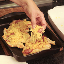 Colocar las pechugas en una fuente para horno. Adornar con rebanadas de tocino, cubitos de manzana cocida y queso rallado. Hornear a 400°F (200°C) durante 5 minutos hasta que se funda el queso.