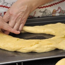 Dividir la masa a la mitad cortándola con un cuchillo (no estirar). Amasar cada parte en forma de bola sobre la mesa, hacer un agujero en medio y estirar para darle forma de dona. Meter los monitos de plástico dentro de la masa por la parte de abajo. Colocar cada rosca sobre una charola refractaria cubierta con papel encerado. Cubrir con una toalla húmeda y dejar inflar durante 60 minutos.