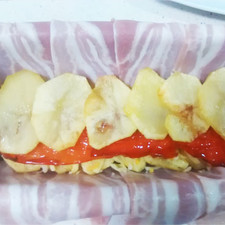 Montamos capas de patatas, pimiento, presa ibérica, pimiento y patatas. Por último añadimos unas rodajas de los huevos duros.