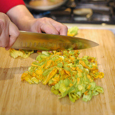 Picar finamente la cebolla, las flores de calabaza, chile serrano y el queso en cuadros a tamaño bocado y los nopales en tiras delgadas. Calentar el aceite en el sartén y sofreír la cebolla picada un par de minutos, agregar las tiras de nopal, chile serrano picado y continuar cociendo 4 minutos más. Añadir las flores de calabaza picada y sazonar con pimienta, sal y dejar cocer unos minutos más. Agregar los cuadros de queso, rectificar sazón y cocer un minutos más. Servir inmediatamente.