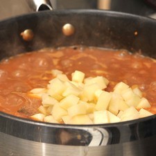 Sazonar con sal al gusto e incorporar la papa. Continuar cociendo con la olla tapada a lumbre bajita durante 15 minutos más o hasta que se cueza la papa.