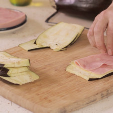 Para armar los rollitos; colocar una rebanada de berenjena sobre la tabla de picar. Colocar un rebanada de queso y una rebanada de jamón enrollar.