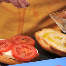 Bañar cada mitad de pan con aceite de oliva.