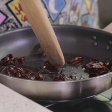 Rociar un sartén con aceite de canola en aerosol, asar las rodajas de chile guajillo cuidando que no se quemen.