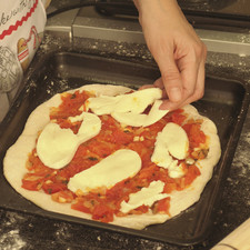 Untar salsa italiana de jitomate sobre la masa utilizando una cuchara y colocar sobre ella el queso mozzarella en rodajas. Sazonar con sal y un poco de aceite de oliva.
