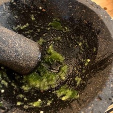 Remoja el molcajete con poca agua, coloca la sal y el chile serrano, comienza a mezclar los ingredientes.