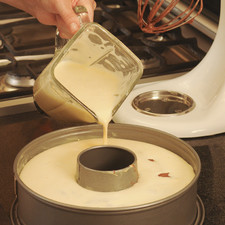 Verter la mezcla para el flan sobre el pastel de chocolate, con cuidado para que quede arriba, procurando que no se revuelvan. Colocar el molde con la mezcla dentro de otro más grande con agua, de manera que el agua cubra al menos la mitad del molde al estilo "baño María". Hornear durante aproximadamente 2 horas en horno precalentado a 375°F (180°C). Probar picando con un palillo de madera para ver si la masa está cocida. Dejar enfriar completamente antes de voltearlo.