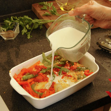 Verter las verduras sobre el bacalao, escurriendo previamente el exceso de aceite. Agregar la leche y hornear en horno pre calentado a 350°F (175°C) durante 15 minutos.