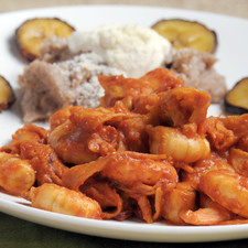 Servir los chilaquiles en un plato con frijoles refritos aderezados con crema y queso parmesano espolvoreado y adornado con rodajas de plátano macho frito.