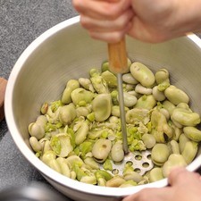 Machacar las habas en una sartén abierta utilizando un machacador de papa hasta que quede un puré fino. También se puede utilizar un pasa purés. Colocar en un tazón.
