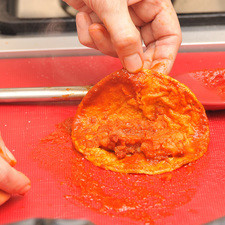 Con una pinza, remojar cada tortilla en la salsa bien caliente, rápidamente. Colocarla sobre un plato, rellenar con una cucharada de papa guisada caliente, doblar la tortilla y acomodar dentro de la canasta cerrando bien la bolsa para que no se escape el calor.