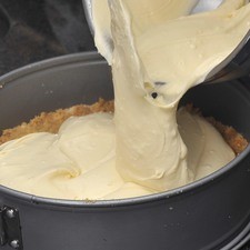 Verter la mezcla sobre la base de migajas. Hornear durante aproximadamente 55 minutos o hasta que el centro esté casi firme. Sacar del horno y pasar un cuchillo o espátula de metal por el borde del molde para despegar el pastel. Dejar enfriar antes de desmoldar.