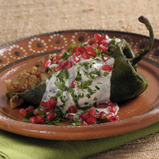 Para servir, calentar el relleno, rellenar los chiles, bañarlos con la nogada y decorar con toques rojos de granada y verdes de perejil picado.