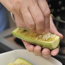 Colocar las cáscaras de las calabacitas en una fuente para horno y rellenarlas con la mezcla de huevo, espolvorear con queso parmesano y hornear a 350°F (175°C) durante 15 minutos hasta que esté dorado el queso.