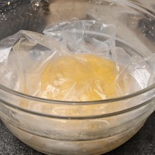 Amasar un poco sobre la mesa y hacer una bola con la masa. Colocar dentro de una bolsa de plástico y dejar reposar 30 minutos a temperatura ambiente.