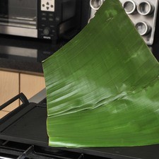 Pasar las hojas de plátano sobre el comal caliente hasta que cambien de color y queden suaves.