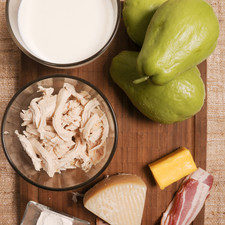 3 chayotes ½ barra de mantequilla (45 gramos) 4 rebanadas de tocino Sal al gusto Pimienta al gusto ¾ taza de pollo desmenuzado 1 cucharada de harina de trigo 1 ½ tazas de leche 200 gramos de queso manchego